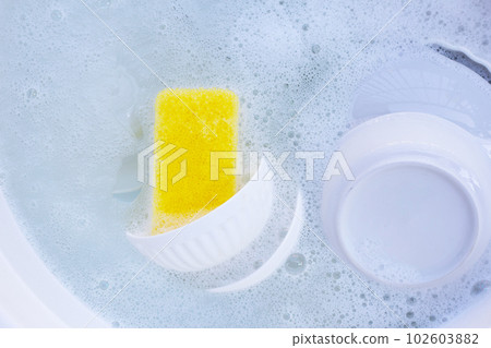 Dishes and bowls in water and bubbles of dishwashing liquid Dishes and bowls in water and bubbles of dishwashing liquid 102603882