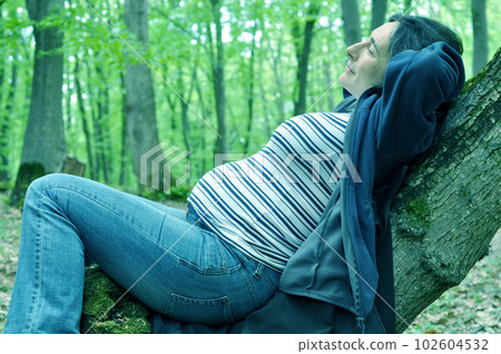 Calm pregnant woman relaxing in the forest Calm pregnant woman relaxing in the forest 102604532