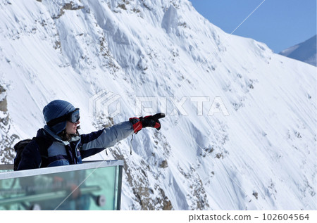 Skier woman in ski clothes and ski googles pointing the direction 102604564