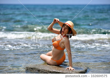 Sexy bikini tanning woman relaxing on the beach with a hat Sexy bikini tanning woman relaxing on the beach with a hat 102604575