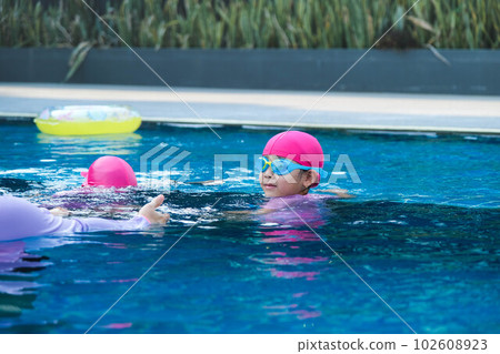 Little girl practicing swimming in the pool. Happy children swimming and playing in the water. summer vacation concept. Little girl practicing swimming in the pool. Happy children swimming and playing in the water. summer vacation concept. 102608923