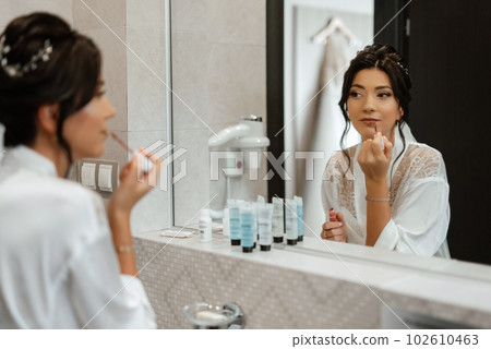 bride in a veil with makeup paints her lips 102610463