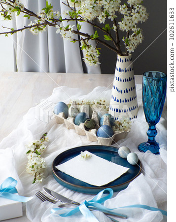 Festive Easter table setting with eggs, flowers and gift box on white background Festive Easter table setting with eggs, flowers and gift box on white background 102611633