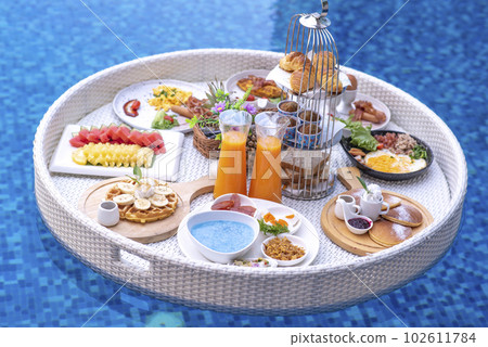 Breakfast in swimming pool, floating breakfast in villa resort. relaxing in calm pool water, healthy breakfast and tropical fruit. 102611784