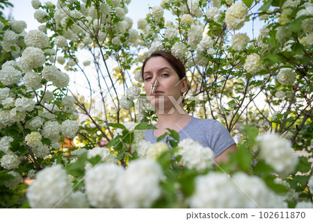 Happy woman with a clothespin on her nose on a walk in a blooming park.  102611870