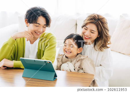 Parent and child looking at a tablet in the living room Parent and child looking at a tablet in the living room 102611953