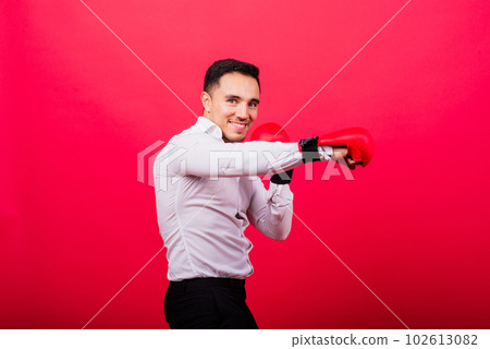 Handsome young businessman with boxing gloves. Studio red background 102613082