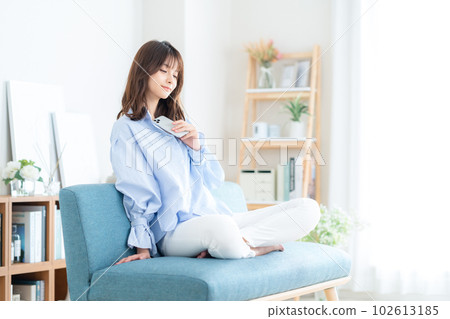 Young woman operating a smartphone on the sofa in the living room 102613185