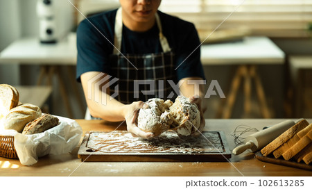 Cropped shot of male baker hands holding freshly baked with variety of bread and dough on the foreground 102613285