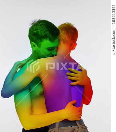 Portrait of two young men, couple hugging against white background. Models posing shirtless with rainbow colored body. Lgbt love 102613332