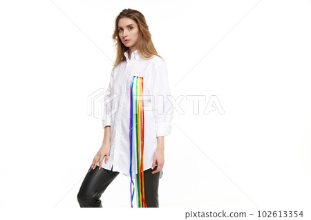Portrait of pretty young girl wearing white shirt with rainbow symbol meaning lgbt support. Model posing against white background 102613354