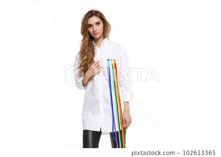 Portrait of young pretty girl in wearing white shirt with rainbow line symbolizing lgbt support. Model posing against white background 102613365