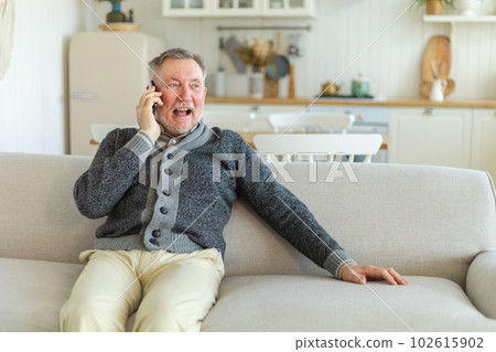 Happy middle aged senior man talking on smartphone with family friends. Older mature grandfather with cell phone talking with grown up children, resting at home. Older generation modern tech usage Happy middle aged senior man talking on smartphone with family friends. Older mature grandfather with cell phone talking with grown up children, resting at home. Older generation modern tech usage 102615902