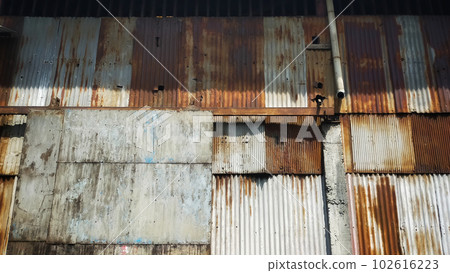 Old building covered with rusty corrugated tin walls and rolling door. 102616223