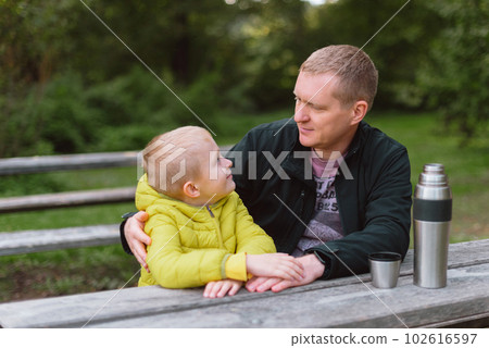 Happy Family: Father And Child Boy Son Playing And Laughing In Autumn Park, Sitting On Wooden Bench And Table. Father And Little Kid Having Fun Outdoors, Playing Together. Father And Son Sitting On A 102616597