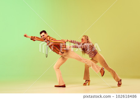 Expressive, talented young couple, man and woman in stylish vintage costumes dancing against gradient green yellow background Expressive, talented young couple, man and woman in stylish vintage costumes dancing against gradient green yellow background 102618486
