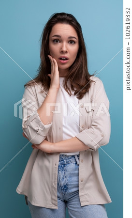 distressed brunette 30 year old female person dressed in shirt and jeans looking at camera on blue distressed brunette 30 year old female person dressed in shirt and jeans looking at camera on blue 102619332