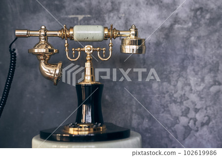 Vintage gold metal phone with dial in focus against a gray concrete wall with space to copy. High quality photo Vintage gold metal phone with dial in focus against a gray concrete wall with space to copy. High quality photo 102619986