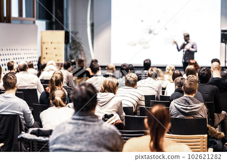 Speaker giving a talk in conference hall at business event. Audience at the conference hall. Business and Entrepreneurship concept. Focus on unrecognizable people in audience. 102621282