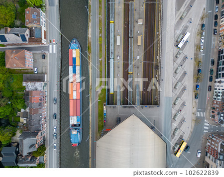 Aerial view of a canal and a railway Station in Belgium. A ferry and cargo ship passes by as the 102622839