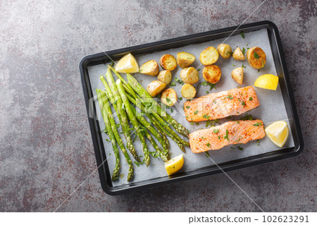Diet food salmon fillet baked with asparagus and new potatoes close-up in a baking sheet. Horizontal top vew 102623291