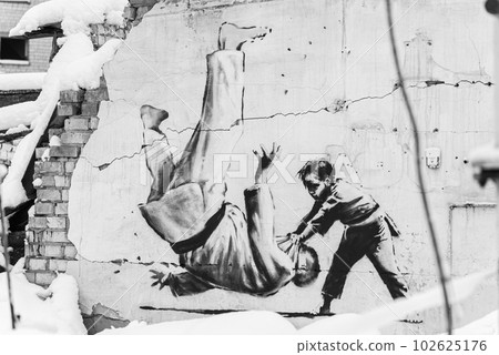 Wall of a destroyed building with Banksy graffiti in Borodyanka, Ukraine, black and white photo 102625176