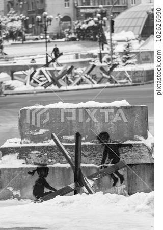 A boy and a girl swing on an anti-tank hedgehog - Banksy graffiti in Kyiv, Ukraine, black and white photo A boy and a girl swing on an anti-tank hedgehog - Banksy graffiti in Kyiv, Ukraine, black and white photo 102626990