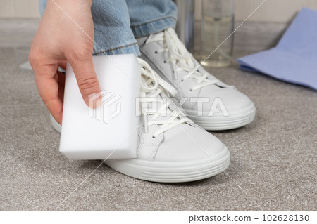 A woman cleans sneakers from dust and dirt with a melamine sponge A woman cleans sneakers from dust and dirt with a melamine sponge 102628130