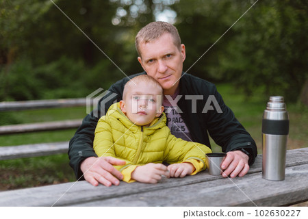 Happy Family: Father And Child Boy Son Playing And Laughing In Autumn Park, Sitting On Wooden Bench And Table. Father And Little Kid Having Fun Outdoors, Playing Together. Father And Son Sitting On A 102630227