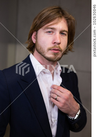 Classic portrait of a man in a jewelry store. The man, wearing a wedding ring and an expensive watch, poses for a business portrait. The stylish and handsome man looks into the camera. 102630846