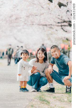 Photo of a family of three standing under a cherry tree 102631409