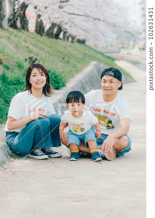 Photo of a family of three standing under a cherry tree 102631431