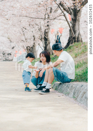 Photo of a family of three standing under a cherry tree 102631435