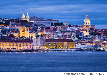 View of Lisbon over Tagus river Alfama district with National Pantheon and Monastery of St. Vincent with passing ferry boat from Almada with ferry in evening twilight. Lisbon, Portugal 102631677
