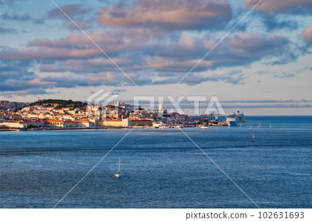 View of Lisbon over Tagus river from Almada with yachts tourist boats and moored cruise liner on sunset with dramatic sky. Lisbon, Portugal View of Lisbon over Tagus river from Almada with yachts tourist boats and moored cruise liner on sunset with dramatic sky. Lisbon, Portugal 102631693