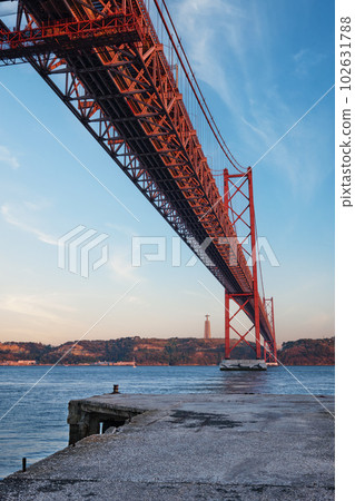 View from under of 25 de Abril Bridge famous tourist landmark over Tagus river, Christ the King monument and quay. Lisbon, Portugal 102631788