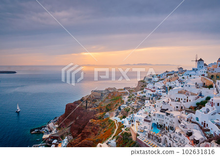 Famous greek iconic selfie spot tourist destination Oia village with traditional white houses and windmills in Santorini island on sunset in twilight, Greece 102631816