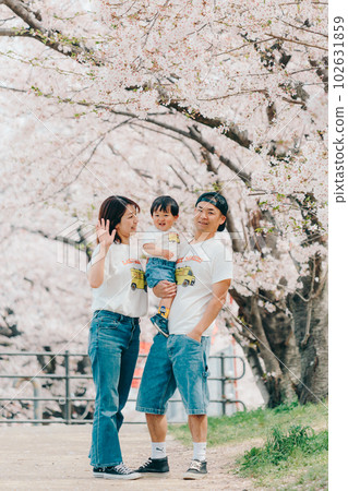 Photo of a family of three standing under a cherry tree 102631859