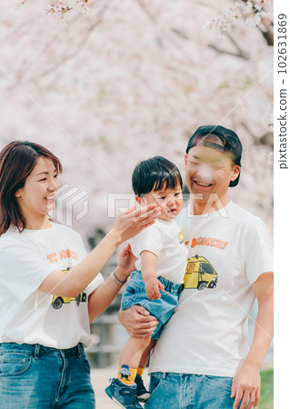 Photo of a family of three standing under a cherry tree 102631869