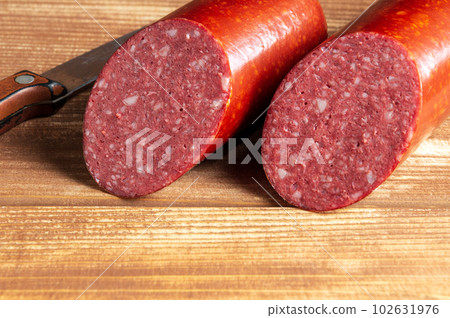 Sliced salami sausage and knife on cutting board closeup. Food preparation idea before the holiday 102631976