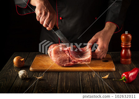 For a fire, raw ribs must be cut into small pieces. Hands of a butcher with a knife in the kitchen. Cooking delicious food for the hotel. For a fire, raw ribs must be cut into small pieces. Hands of a butcher with a knife in the kitchen. Cooking delicious food for the hotel. 102632011