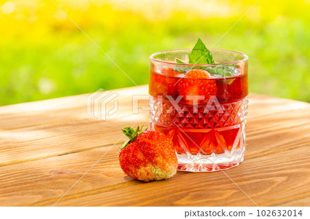 Strawberries on the table and a fresh drink with mint on sunny day Strawberries on the table and a fresh drink with mint on sunny day 102632014