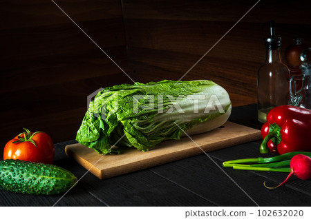 Fresh napa cabbage on a restaurant kitchen cutting board before preparing diet salad with vegetables. Free advertising space Fresh napa cabbage on a restaurant kitchen cutting board before preparing diet salad with vegetables. Free advertising space 102632020