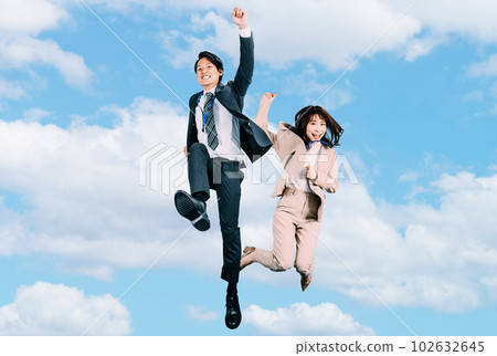 Male and female Japanese businessmen jumping in summer blue sky 102632645