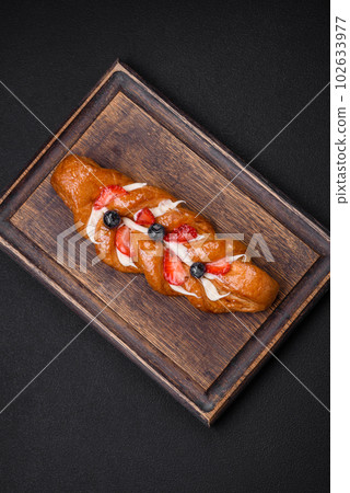 Delicious fresh crispy pastry in the form of a pigtail with strawberries and blueberries Delicious fresh crispy pastry in the form of a pigtail with strawberries and blueberries 102633977
