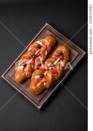Delicious fresh crispy pastry in the form of a pigtail with strawberries and blueberries Delicious fresh crispy pastry in the form of a pigtail with strawberries and blueberries 102633981