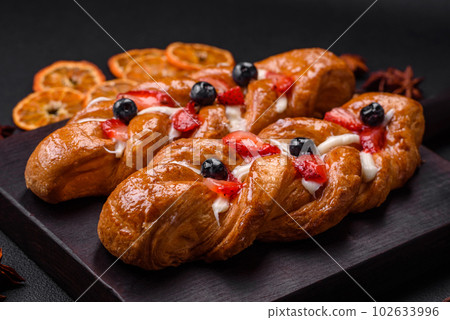 Delicious fresh crispy pastry in the form of a pigtail with strawberries and blueberries Delicious fresh crispy pastry in the form of a pigtail with strawberries and blueberries 102633996