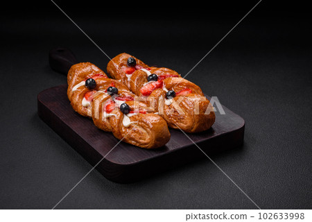 Delicious fresh crispy pastry in the form of a pigtail with strawberries and blueberries Delicious fresh crispy pastry in the form of a pigtail with strawberries and blueberries 102633998
