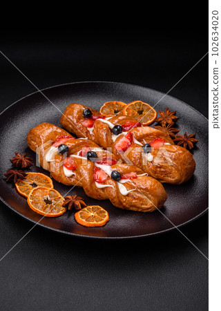 Delicious fresh crispy pastry in the form of a pigtail with strawberries and blueberries Delicious fresh crispy pastry in the form of a pigtail with strawberries and blueberries 102634020