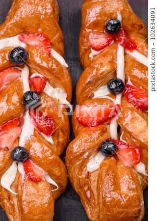 Delicious fresh crispy pastry in the form of a pigtail with strawberries and blueberries 102634091